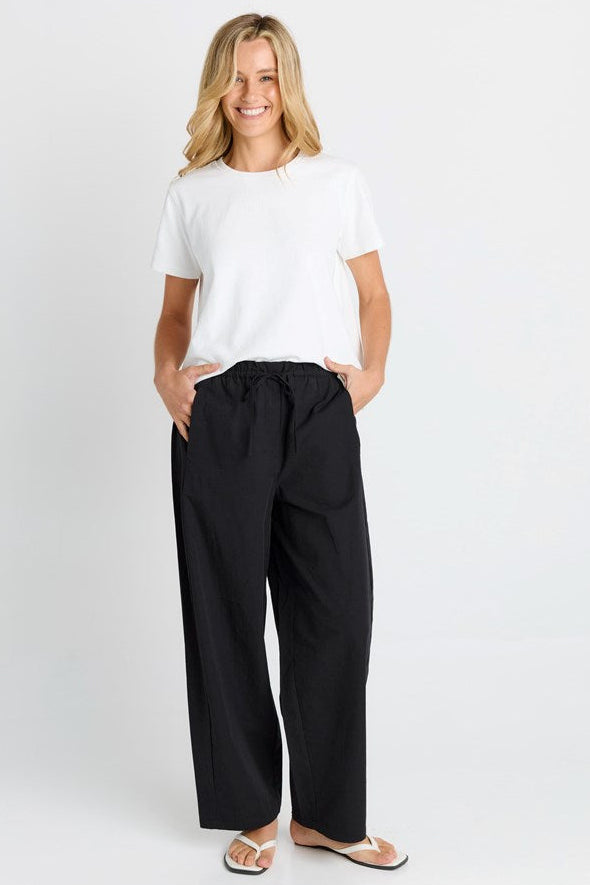 Image of a model wearing Pants. Product name - Patsy Pant Black in Black colour by brand - Betty Basics