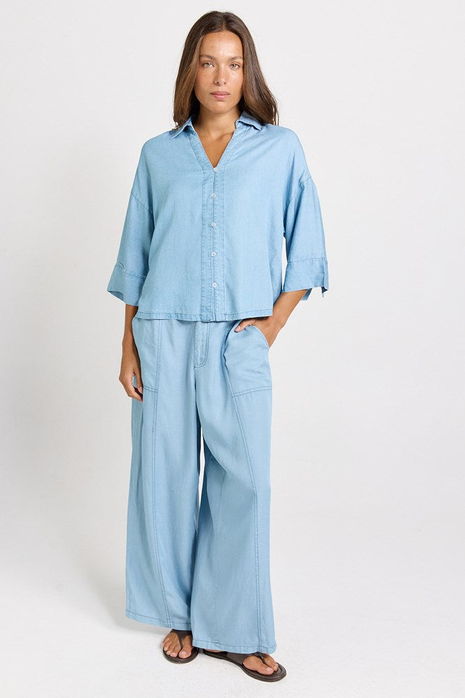 Image of a model wearing Pants. Product name - Emmy Lyocell Wide Leg Pant Mid Wash in Mid Wash colour by brand - Betty Basics