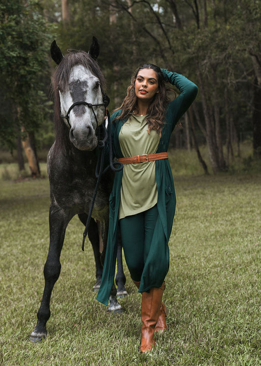 Image of a model wearing Tops. Product name - Susie Oversized Asymmetrical Bamboo Top Olive in Olive colour by brand - Lou Lou