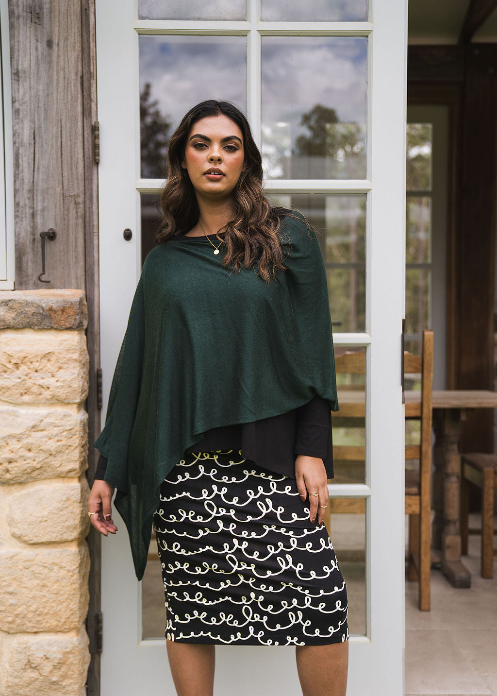 Image of a model wearing Tops. Product name - Carrie Cashmere & Bamboo Knit Poncho Dark Green in Dark Green colour by brand - Lou Lou