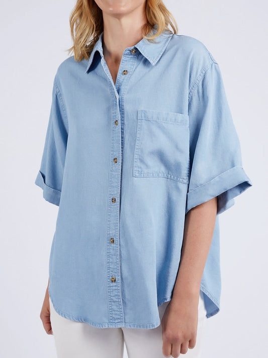 Image of a model wearing Tops. Productname: ELM BLISSFUL CHAMBRAY SHORT SLEEVE SHIRT in Blue colour by brand - Elm
