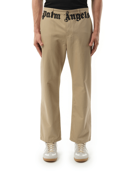 Image of a model wearing Pants. Productname: PALM ANGELS Classic Logo Chino Pants in BROWN colour by brand - PALM ANGELS