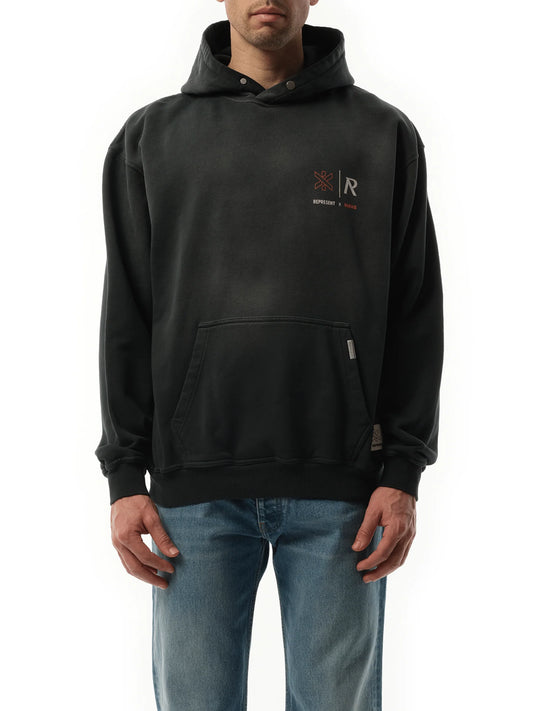 Image of a model wearing Outerwear. Product name - Represent x Marais Logo Lock Up Hoodie in Black colour by brand - REPRESENT