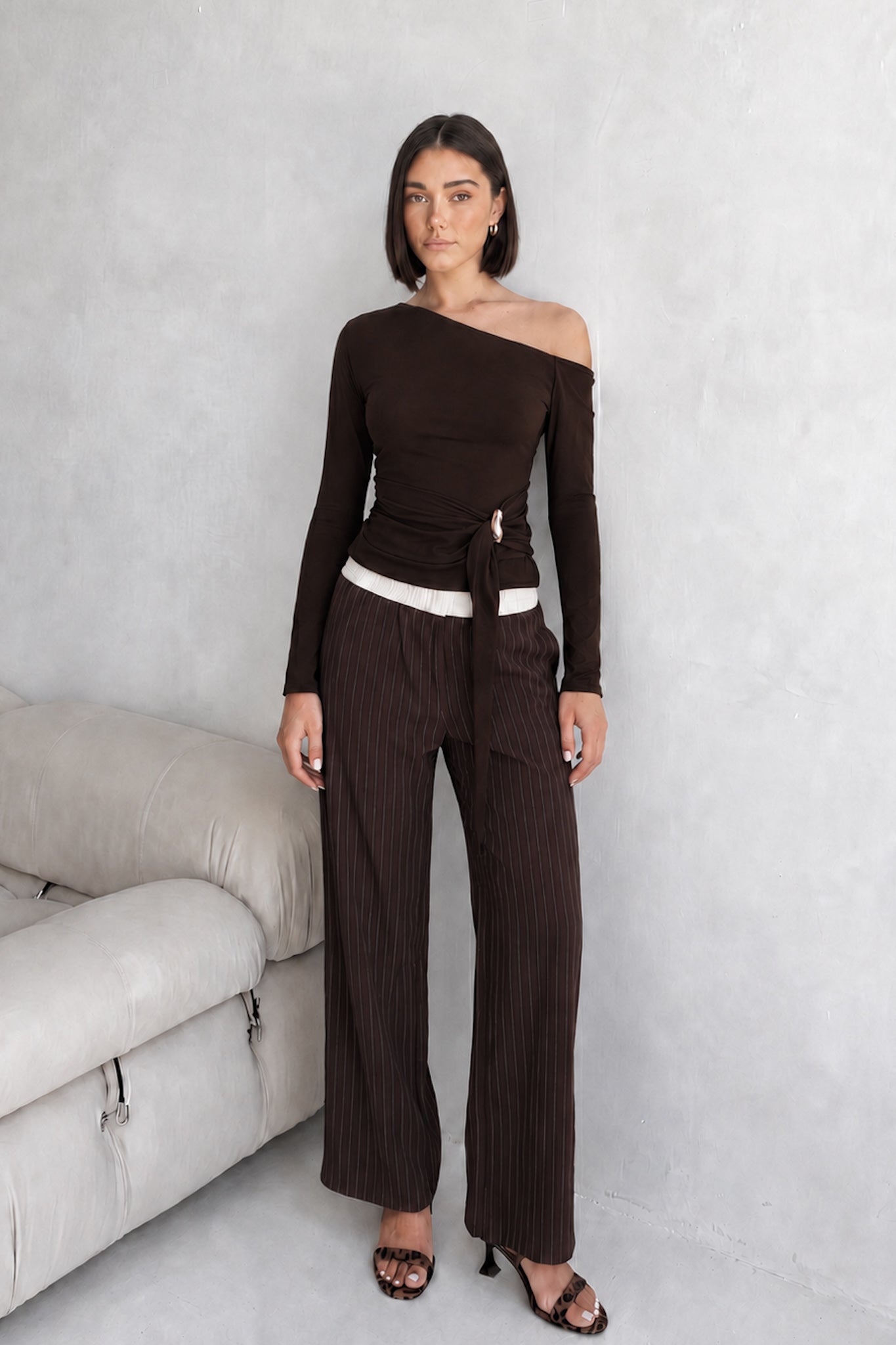 Image of a model wearing Tops. Product name - Jayn Brown Asymmetric Top in Brown colour by brand - HEYCHIC