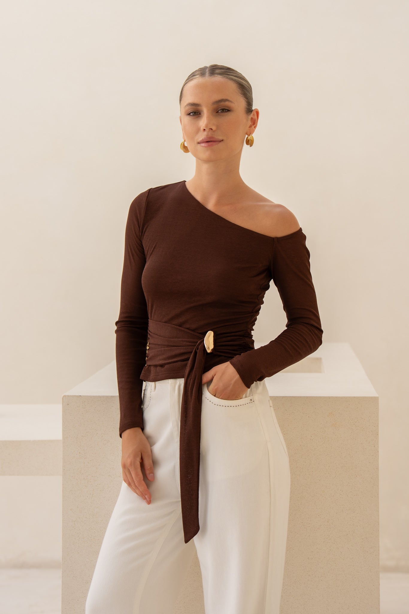 Image of a model wearing Tops. Product name - Jayn Brown Asymmetric Top in Brown colour by brand - HEYCHIC