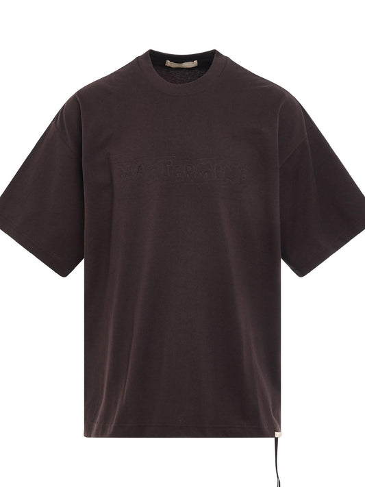 Image of a model wearing Tops. Productname: MASTERMIND Debossed Word T-Shirt in BROWN colour by brand - MASTERMIND