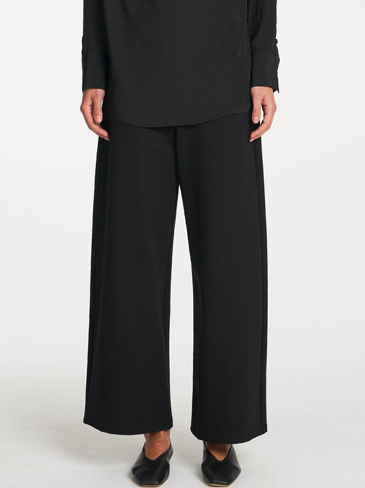 Image of a model wearing Pants. Product name - MELA PURDIE PALAZZO PANT in Black colour by brand - Mela Purdie