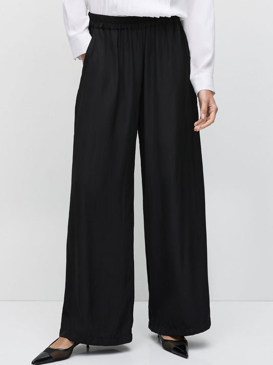 Image of a model wearing Pants. Product name - Mela Purdie Maxi Pace Pant in Black colour by brand - Mela Purdie
