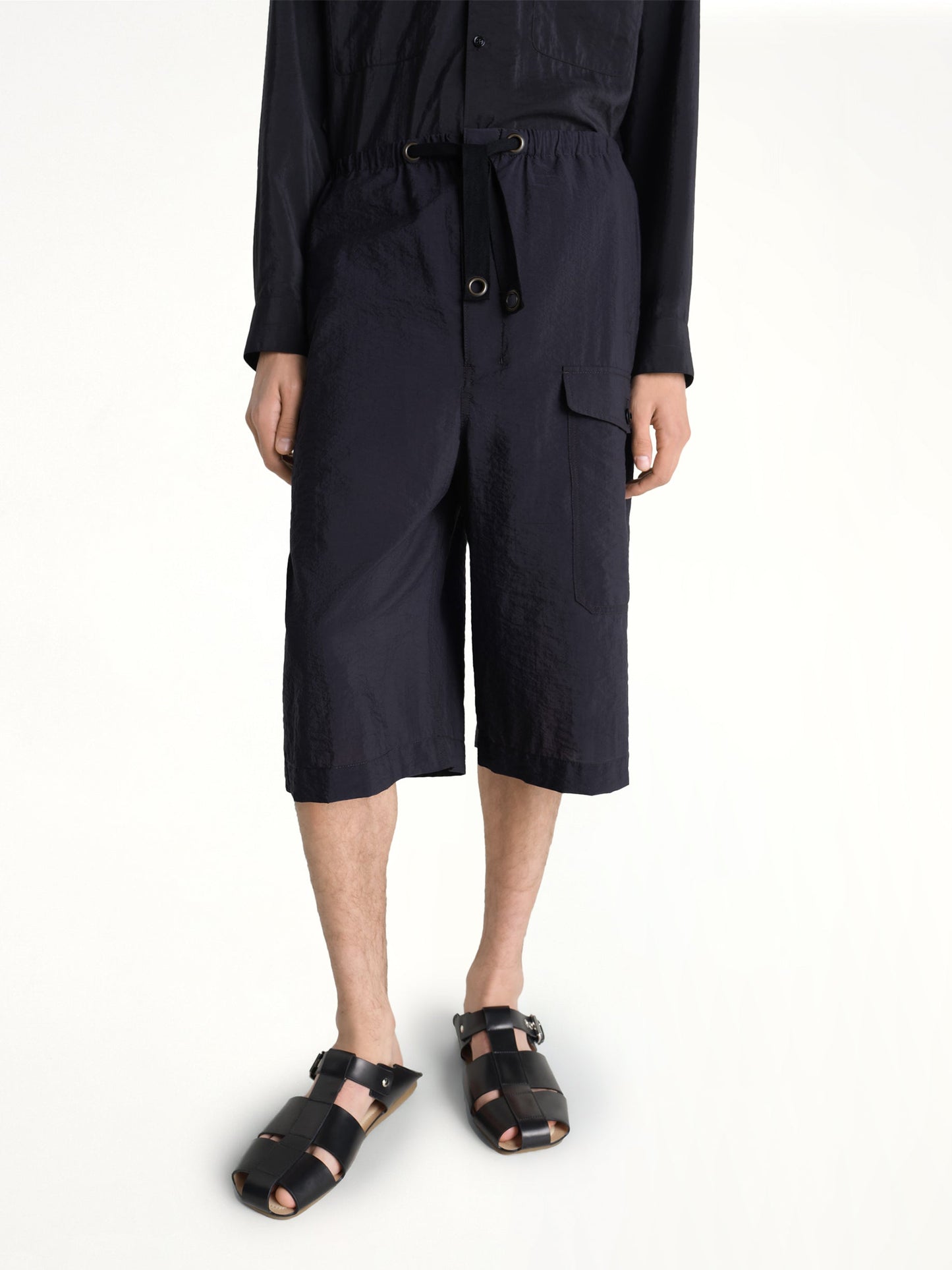 Image of a model wearing Shorts. Product name - Cargo Easy Shorts in Black colour by brand - LEMAIRE