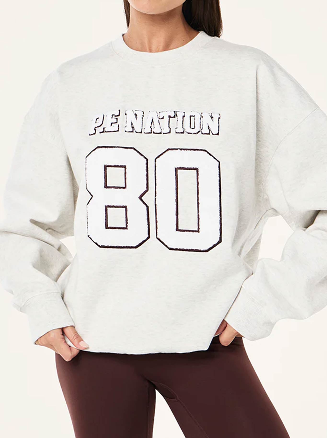 Image of a model wearing Tops. Product name - P.E NATION ELYSIAN 2.0 SWEAT in Snow colour by brand - P.E Nation