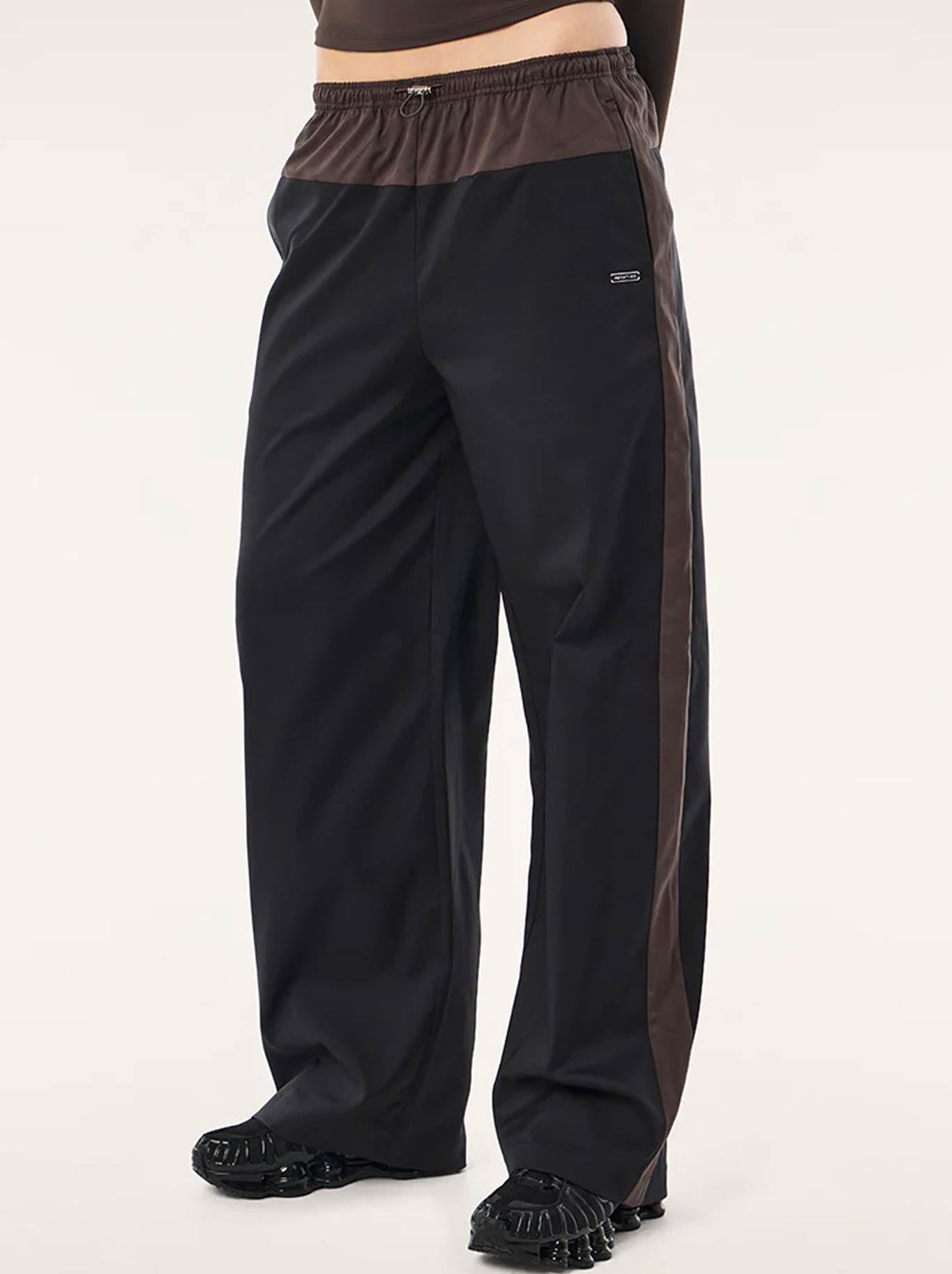 Image of a model wearing Pants. Product name - P.E NATION HALO PANT in Black Coffee colour by brand - P.E Nation