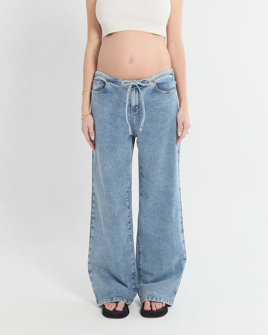 Image of a model wearing Pants. Product name - Relaxed Wide Leg Drawstring Jeans in colour by brand - Soon Maternity