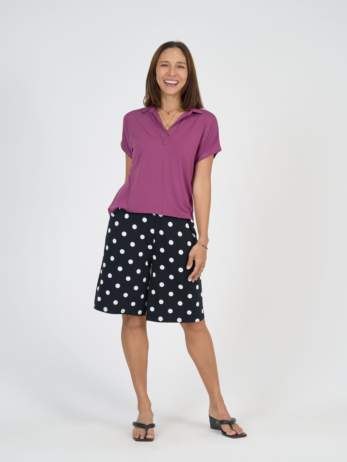 Image of a model wearing Tops. Product name - Rush Bamboo Short Sleeve Collared Polo Top Plum in Plum colour by brand - Lou Lou