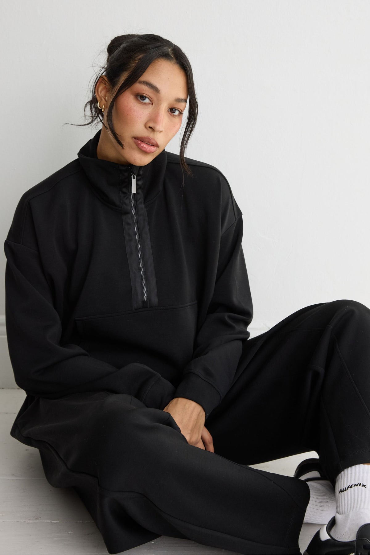 Image of a model wearing Outerwear. Product name - Soft Luxury 1/2 Zip Sweater in Black colour by brand - All Fenix