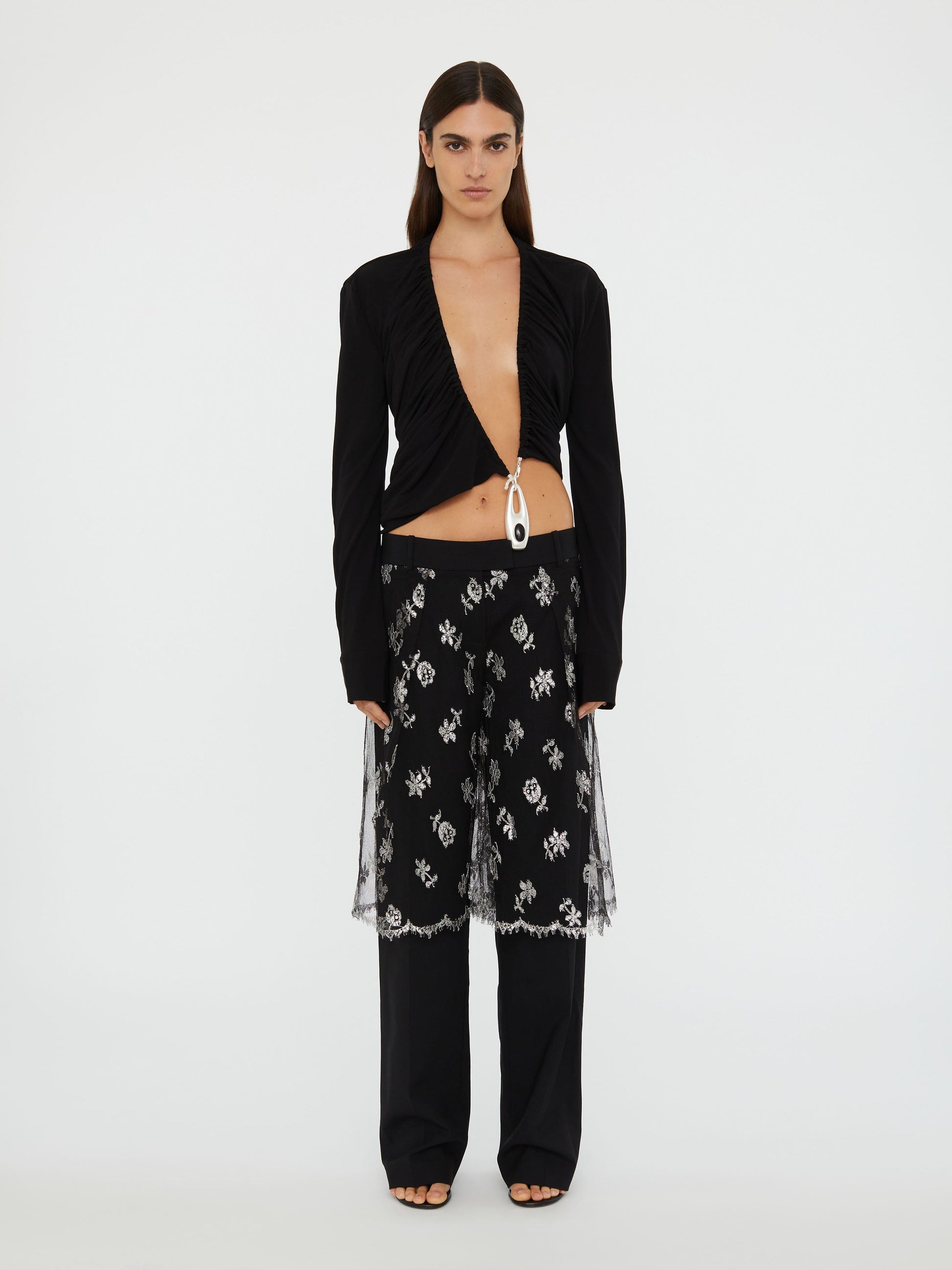 Image of a model wearing Pants. Product name - Lace Sarong Wool Trouser in Black colour by brand - Christopher Esber