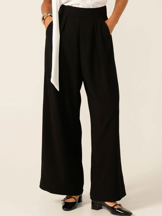 Image of a model wearing Pants. Product name - SACHA DRAKE PLEATED TROUSER in Black colour by brand - Sacha Drake Pty Ltd