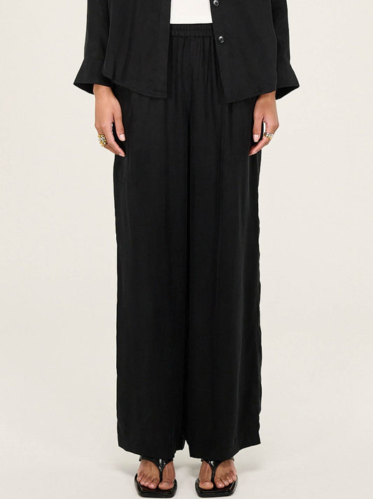 Image of a model wearing Pants. Productname: Staple The Label Silvie Cupro Relaxed Pants in Black colour by brand - Staple