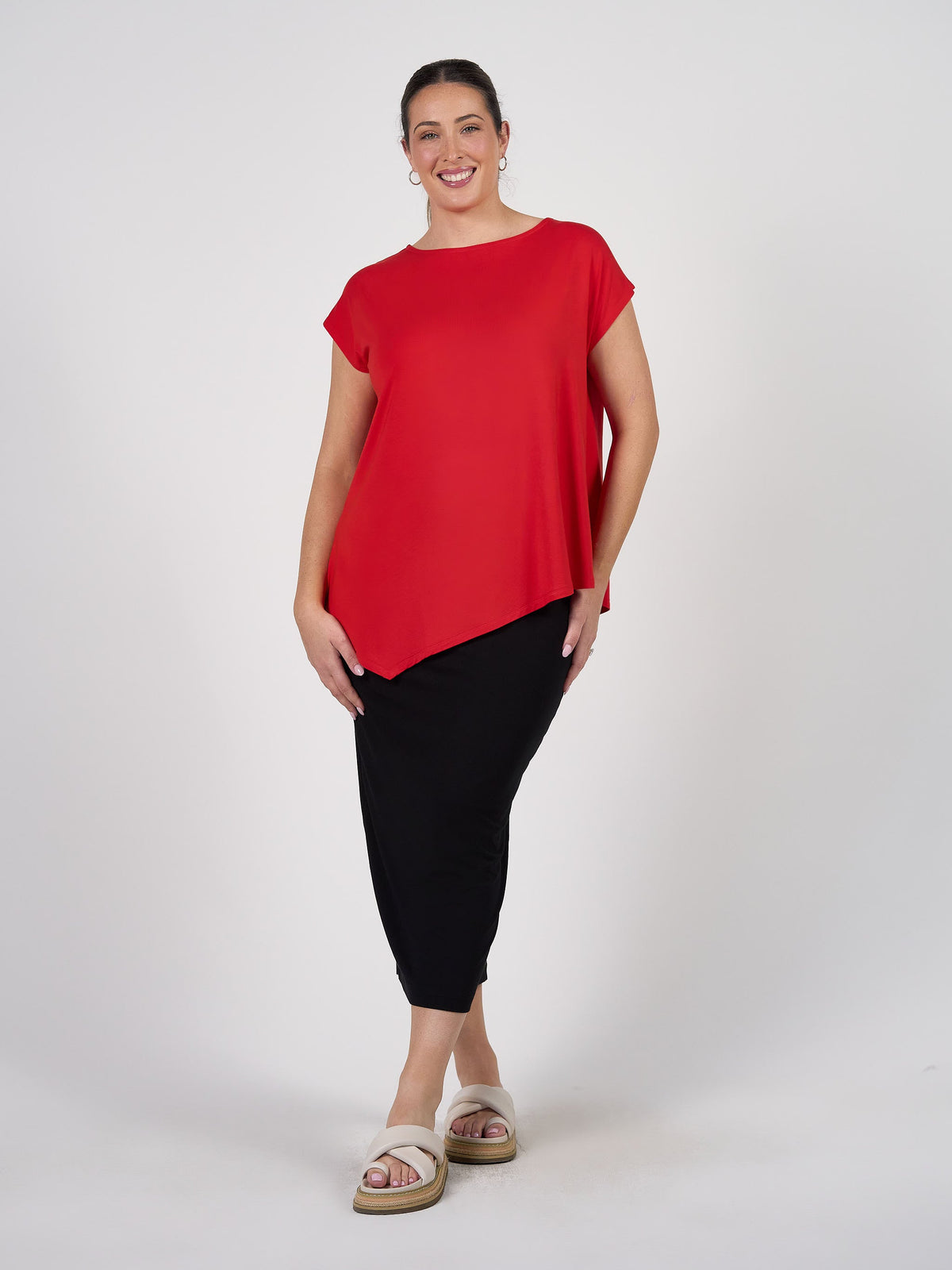 Image of a model wearing Tops. Product name - Toni Asymmetrical Bamboo T-Shirt Fiery Red in Fiery Red colour by brand - Lou Lou