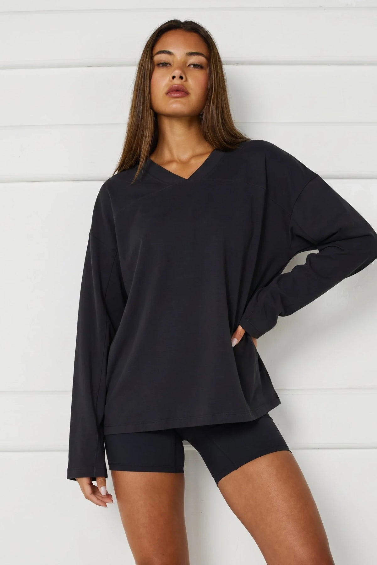 Image of a model wearing Tops. Product name - Oversized V-Neck Long Sleeve in Black colour by brand - All Fenix