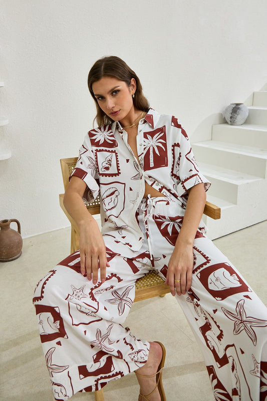 Image of a model wearing Pants. Productname: Heychic Mira Sea Shells Tropical Wide Leg Pants in Brown colour by brand - Heychic