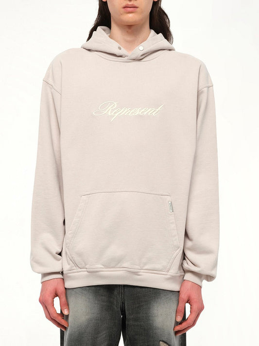 Image of a model wearing Outerwear. Productname: REPRESENT Script Logo Hoodie in Concrete colour by brand - REPRESENT