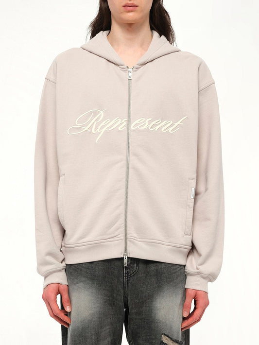 Image of a model wearing Outerwear. Productname: REPRESENT Script Logo Zip Hoodie in Concrete colour by brand - REPRESENT
