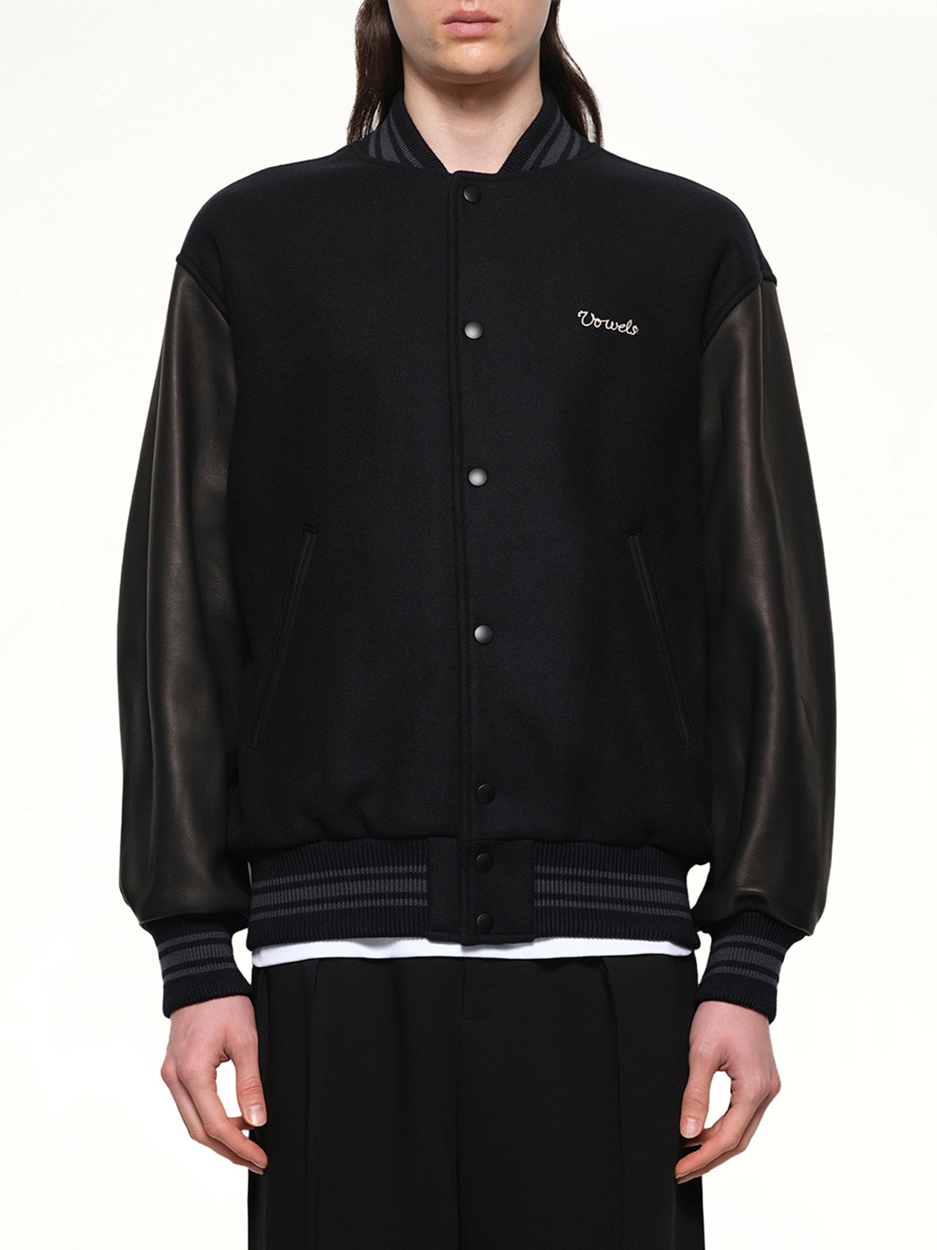 Image of a model wearing Outerwear. Productname: VOWELS Varsity Jacket in Black colour by brand - VOWELS