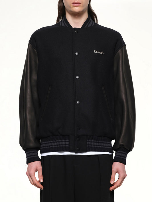 Image of a model wearing Outerwear. Productname: VOWELS Varsity Jacket in Black colour by brand - VOWELS