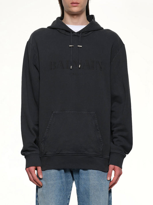 Image of a model wearing Outerwear. Product name - Balmain Vintage Emblem Hoodie in Black colour by brand - BALMAIN