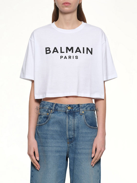 Image of a model wearing Tops. Productname: BALMAIN Logo Print Cropped T-Shirt in WHITE colour by brand - BALMAIN