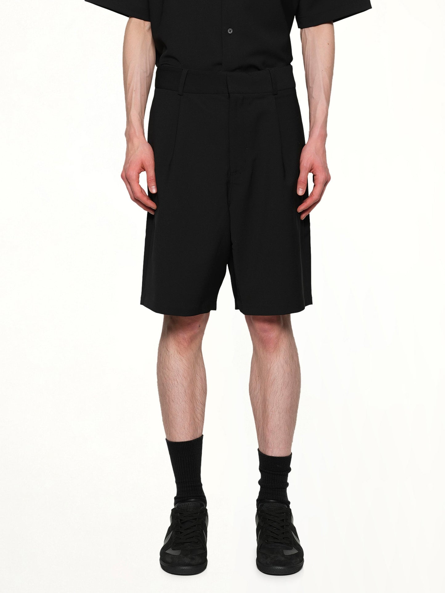 Image of a model wearing Shorts. Product name - Tailored Shorts in Black colour by brand - ENTIRE STUDIOS