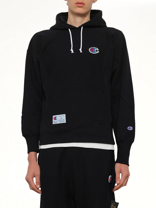 Image of a model wearing Outerwear. Product name - Undercover X Champion Hoodie in Black colour by brand - UNDERCOVER