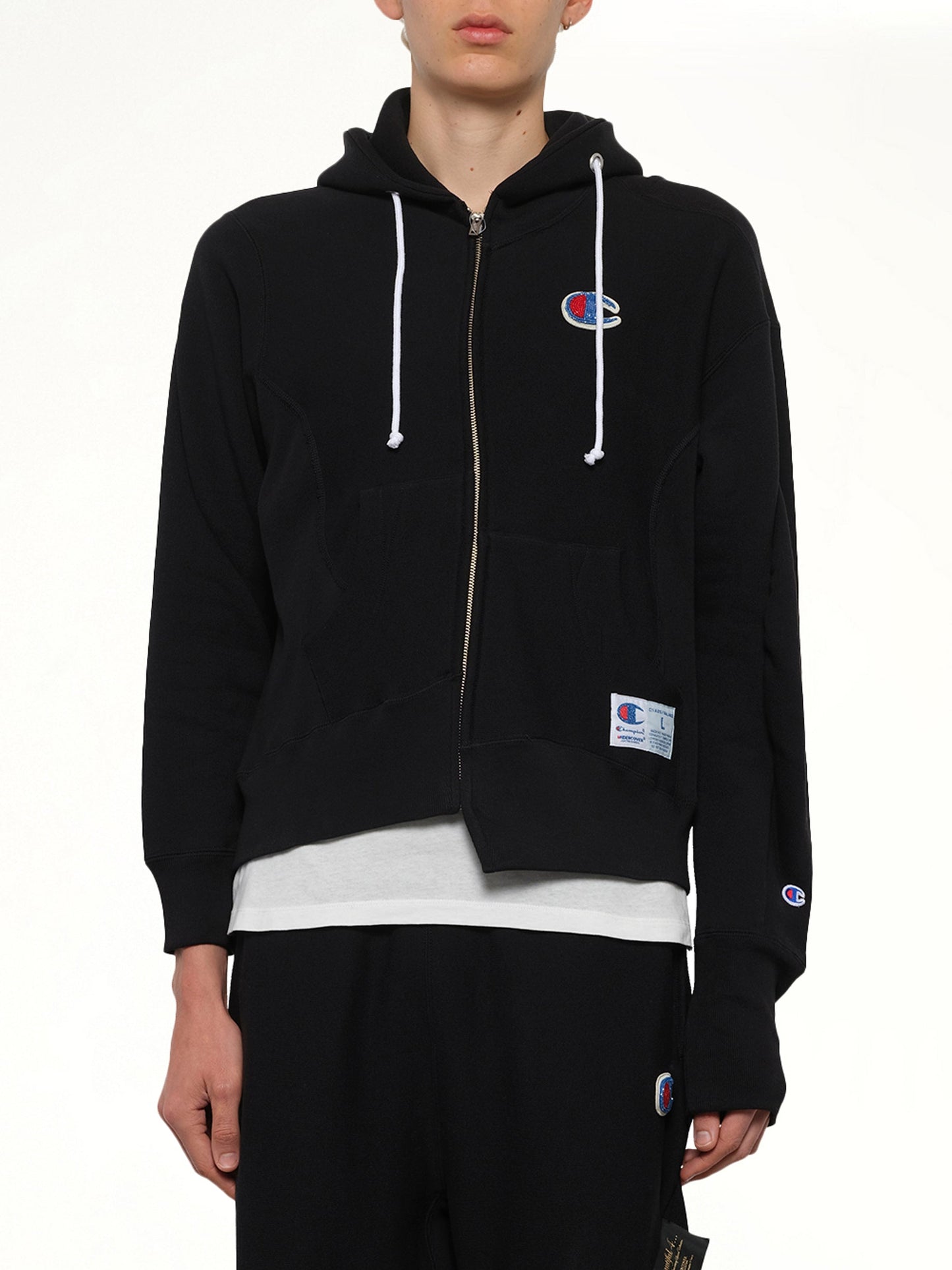 Image of a model wearing Outerwear. Product name - Undercover X Champion Zip Hoodie in Black colour by brand - UNDERCOVER