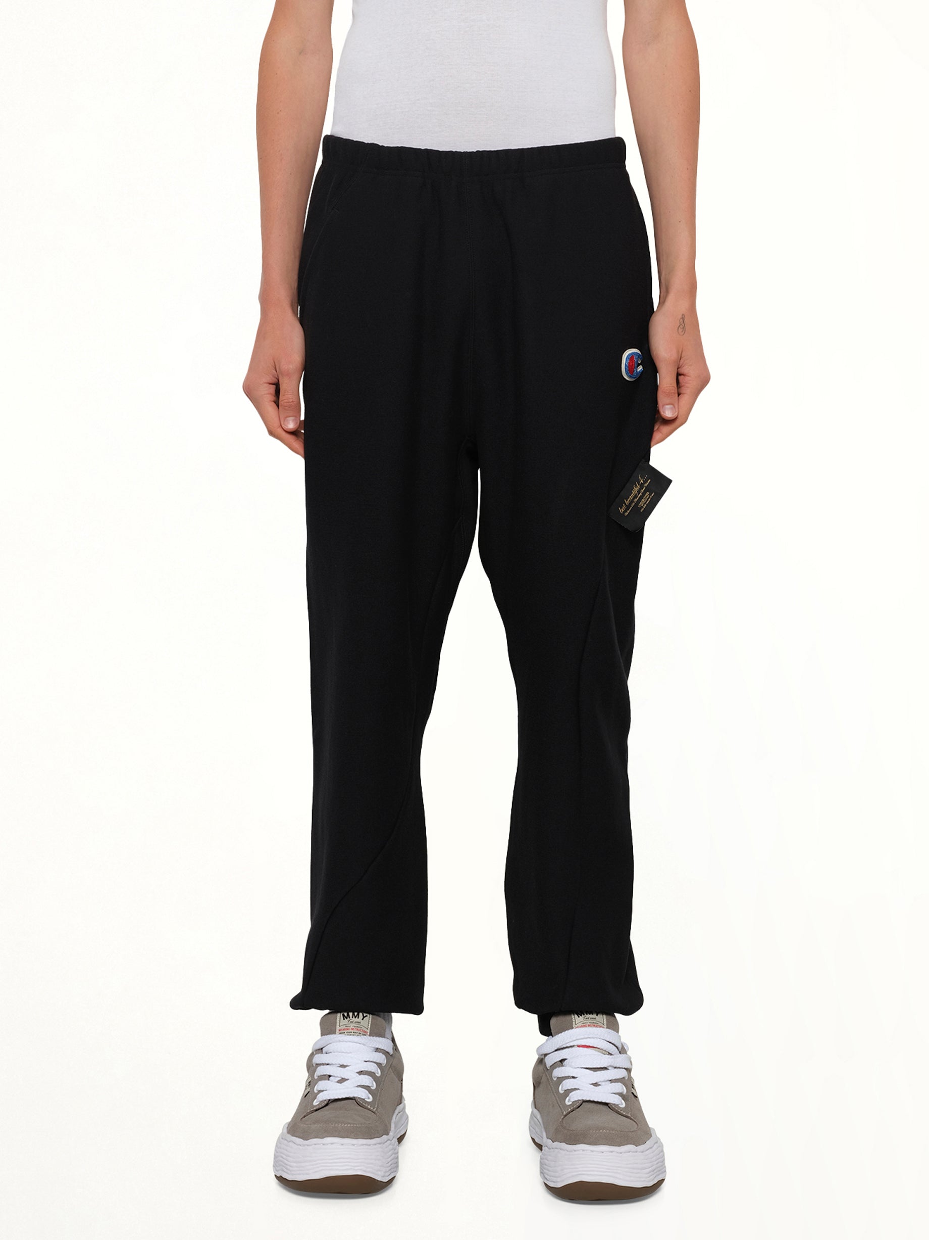 Image of a model wearing Pants. Product name - Undercover X Champion Sweatpants in Black colour by brand - UNDERCOVER