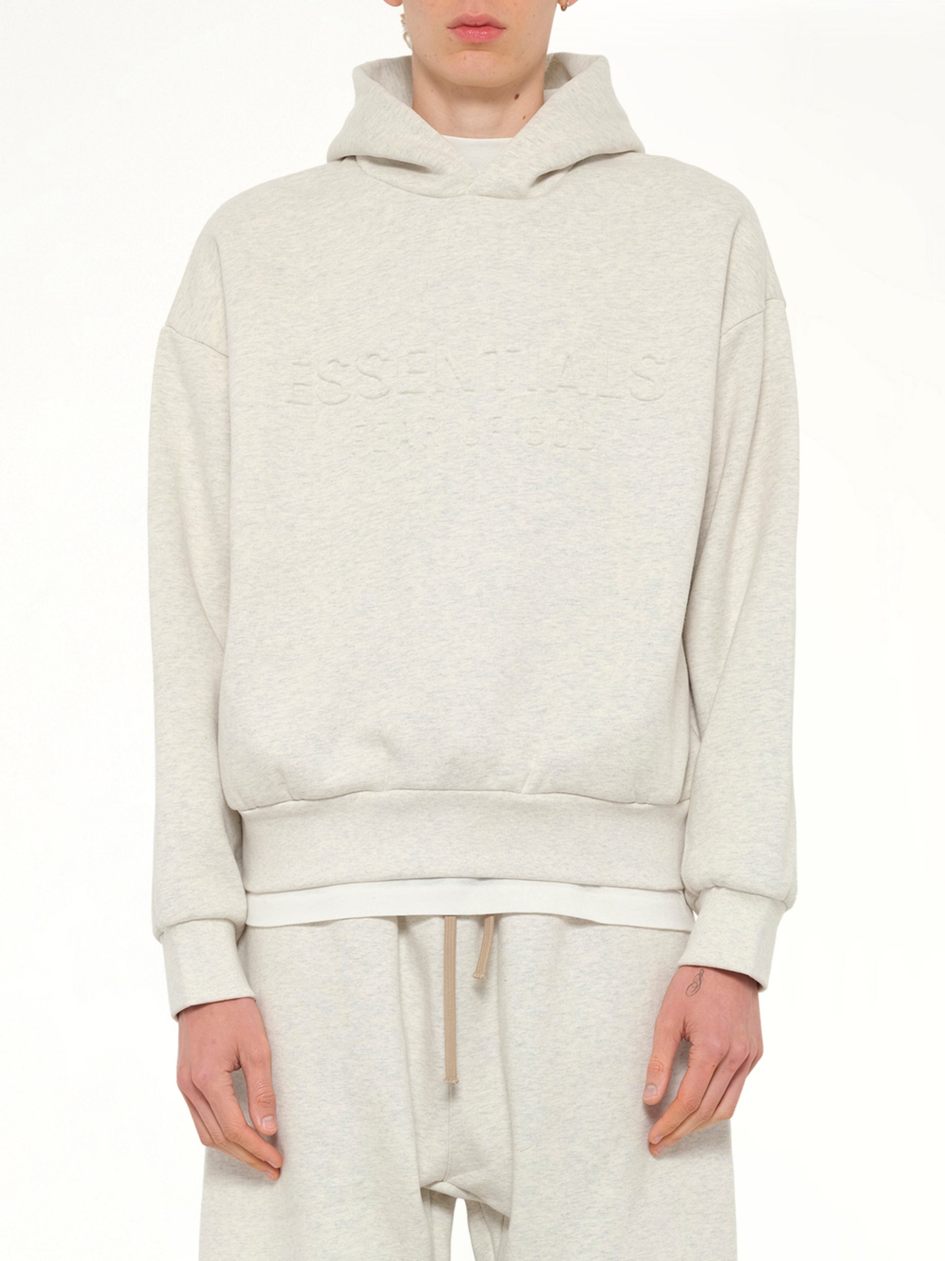 Image of a model wearing Outerwear. Product name - Classic Hoodie in Beige colour by brand - FEAR OF GOD ESSENTIALS