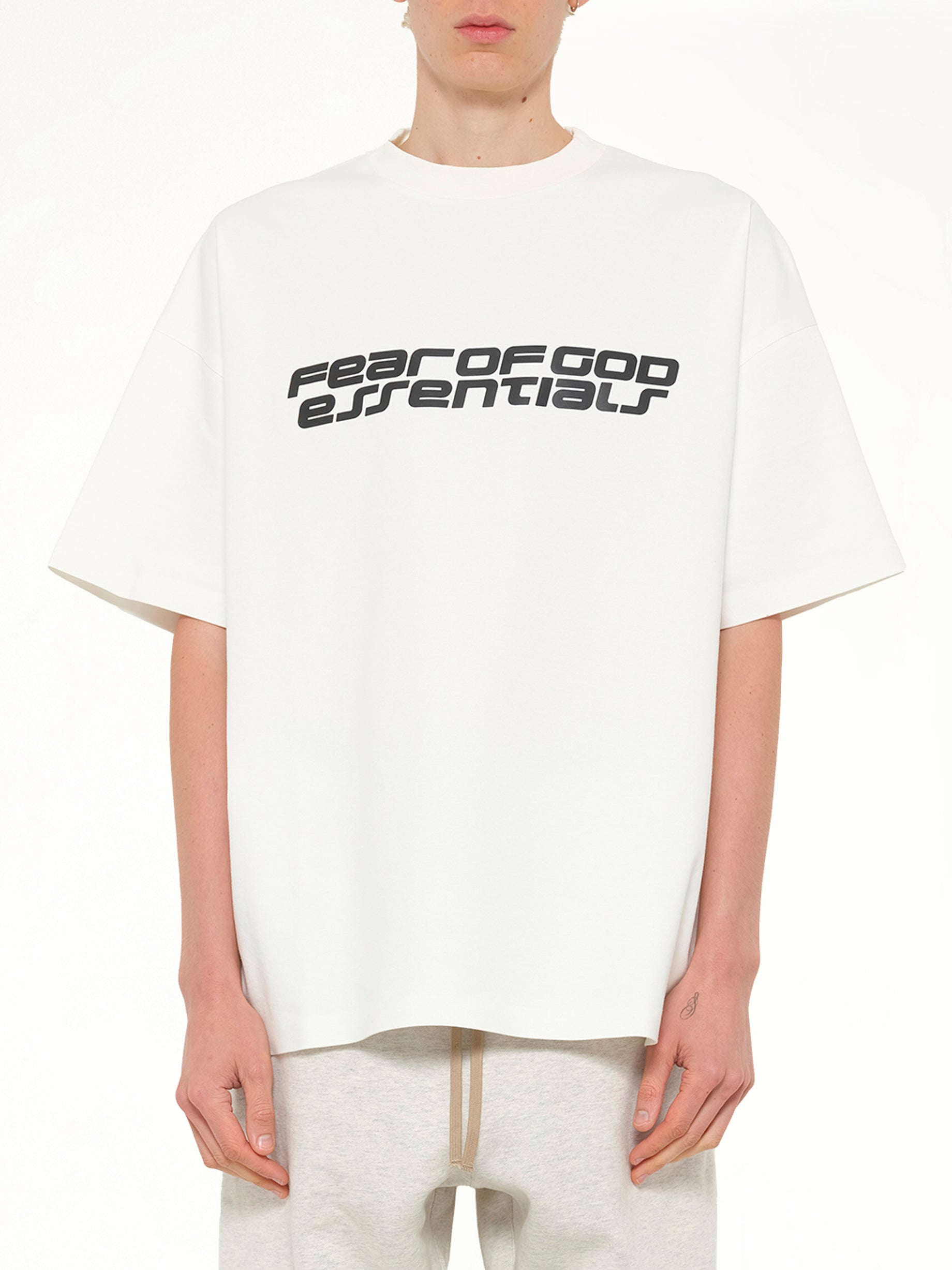 Image of a model wearing Tops. Product name - 90's Short Sleeve T-Shirt in Ivory colour by brand - FEAR OF GOD ESSENTIALS