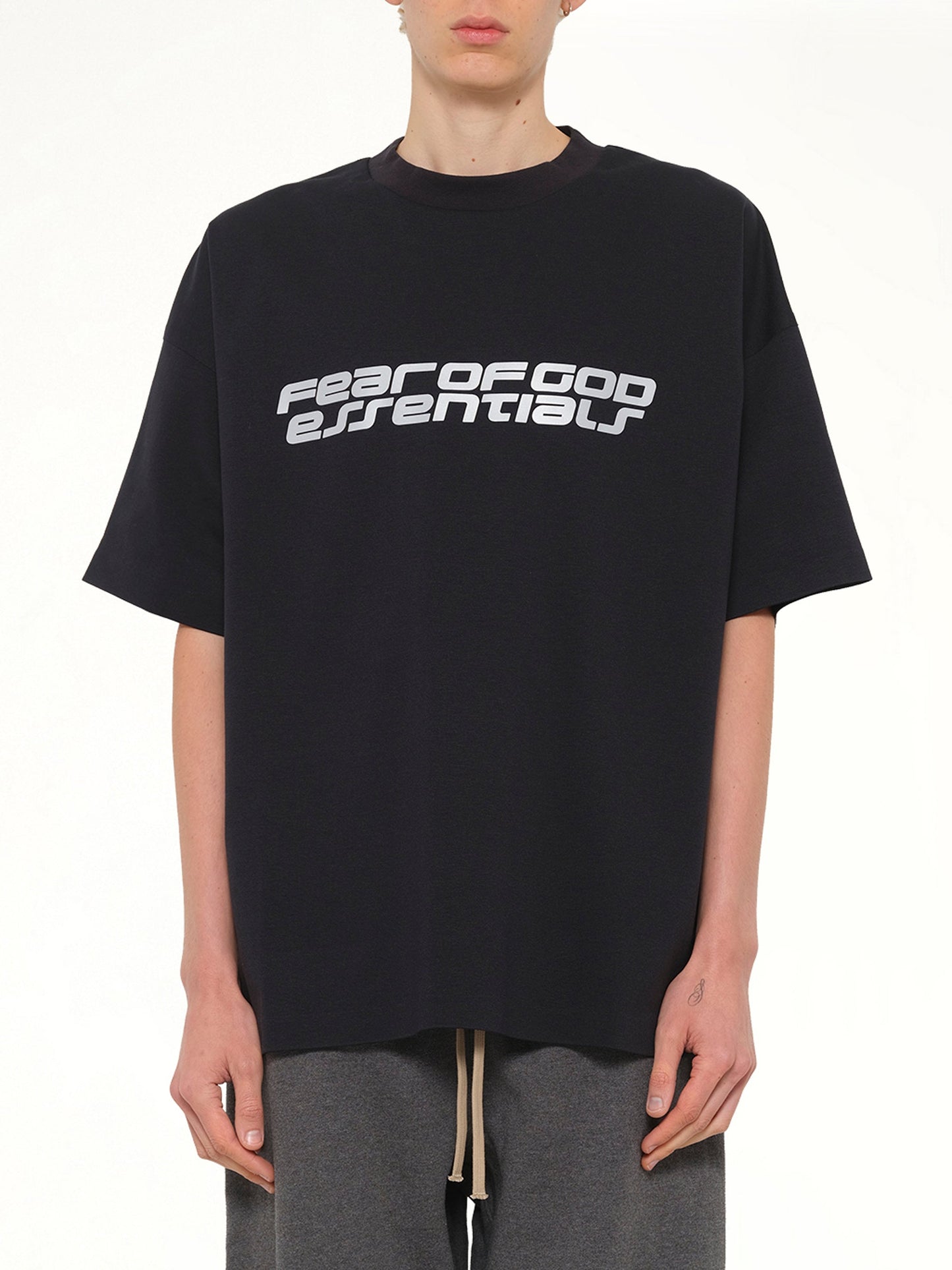Image of a model wearing Tops. Product name - 90's Short Sleeve T-Shirt in Black colour by brand - FEAR OF GOD ESSENTIALS