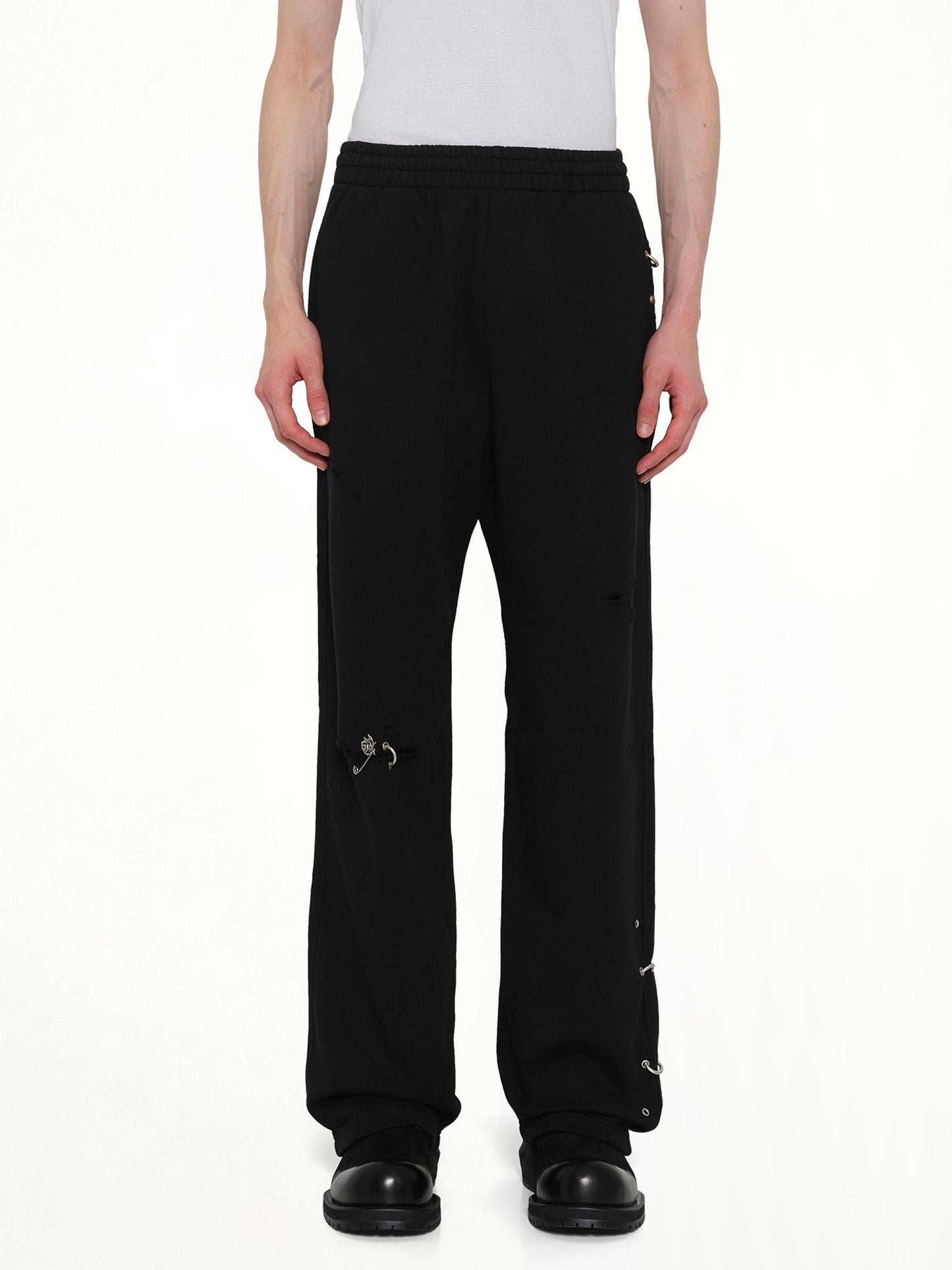 Image of a model wearing Pants. Product name - Piercing Detail Sweatpants in Black colour by brand - WE11DONE