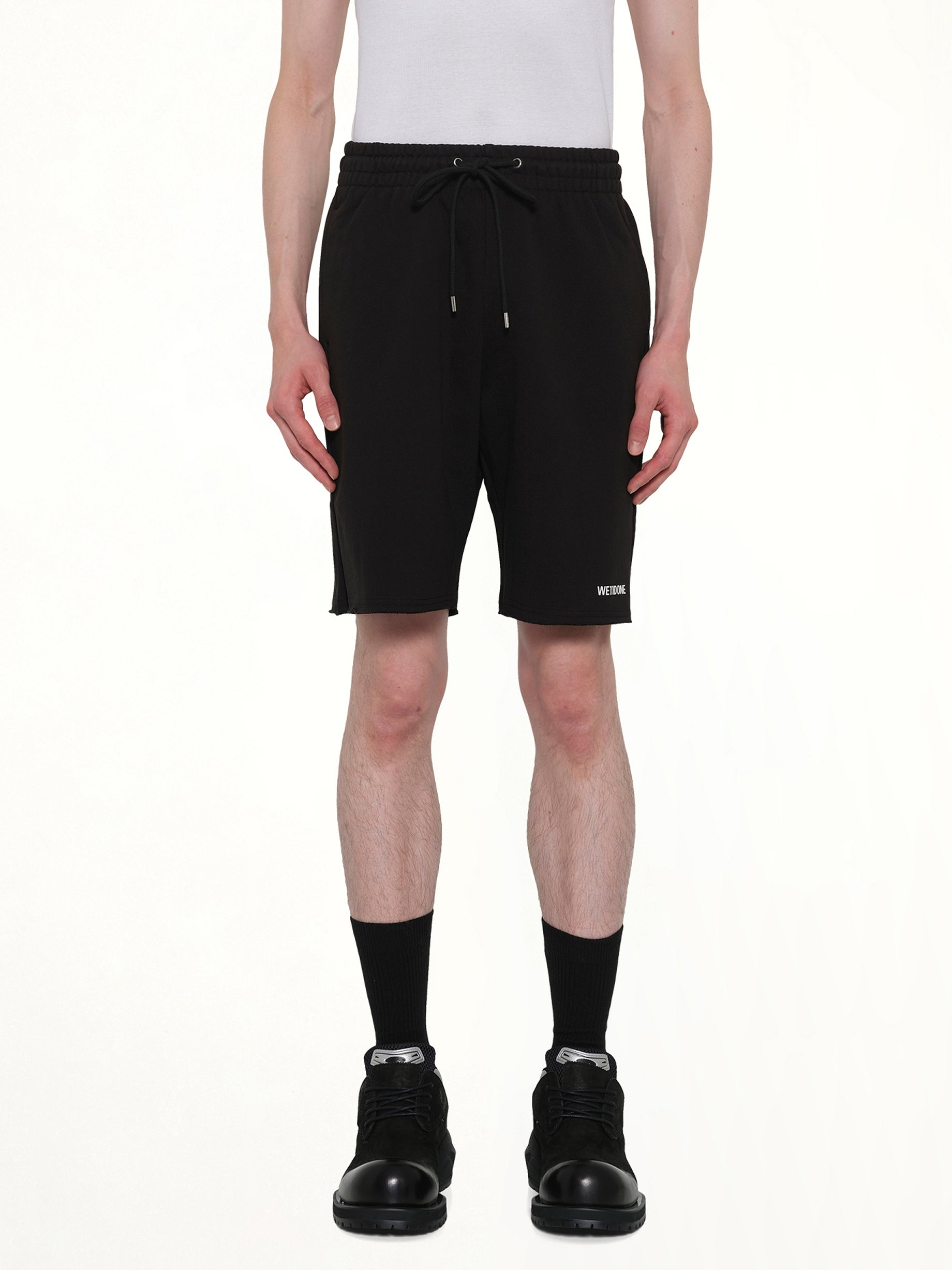 Image of a model wearing Shorts. Product name - Basic Logo Shorts in Black colour by brand - WE11DONE