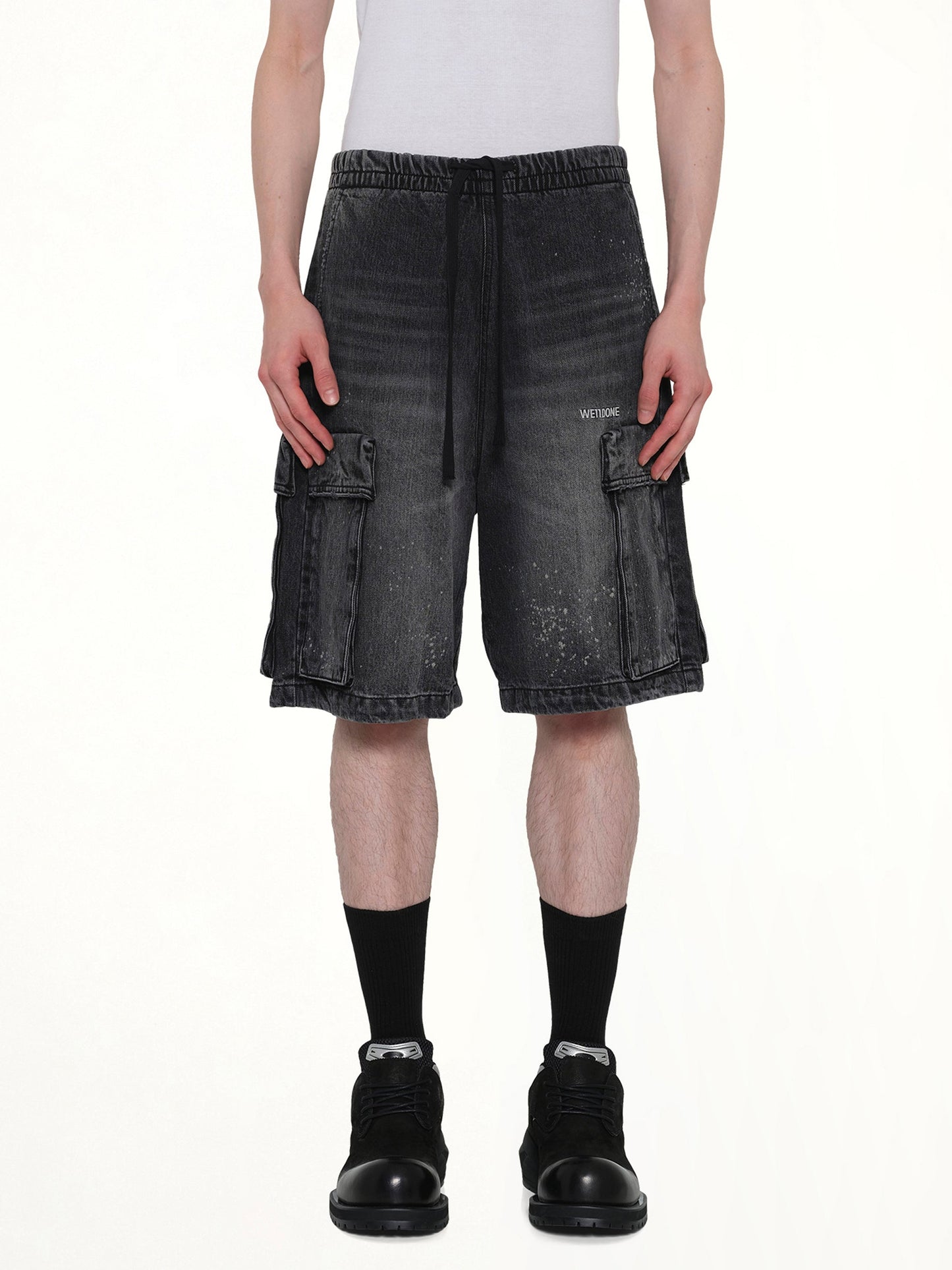 Image of a model wearing Shorts. Product name - Pocket Shorts in Black colour by brand - WE11DONE