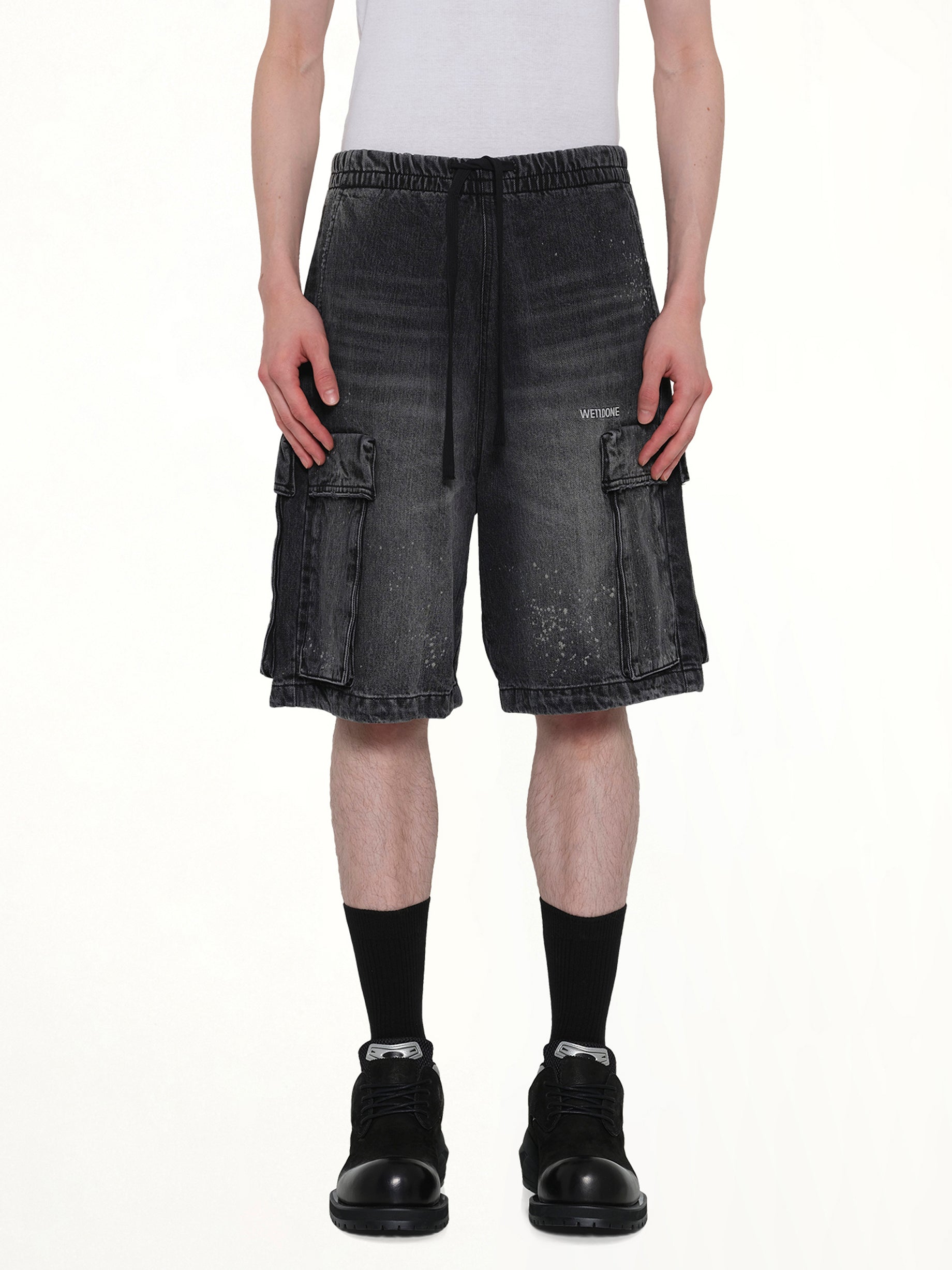 Image of a model wearing Shorts. Product name - Pocket Shorts in Black colour by brand - WE11DONE