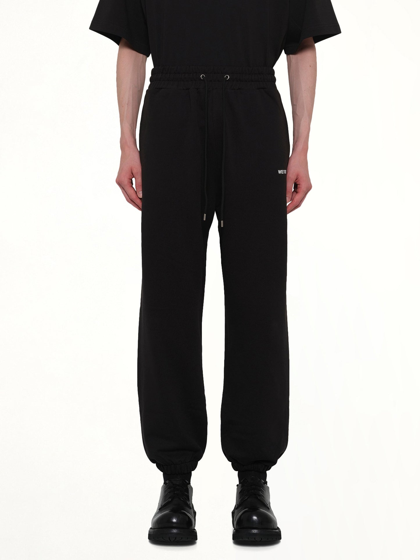 Image of a model wearing Pants. Product name - Logo Medium Lounge Pants in Black colour by brand - WE11DONE