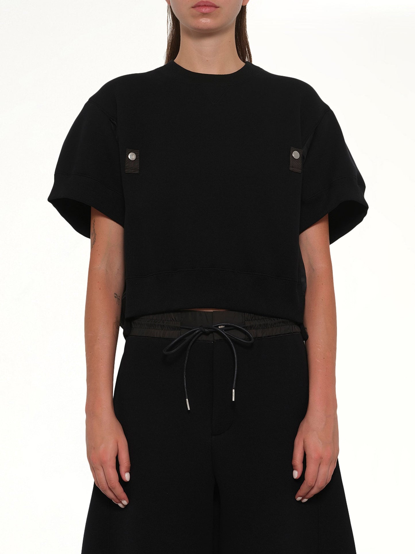 Image of a model wearing Outerwear. Product name - Sponge Sweat Short Sleeve Pullover in Black colour by brand - SACAI