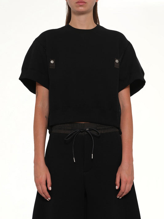 Image of a model wearing Outerwear. Product name - Sponge Sweat Short Sleeve Pullover in Black colour by brand - SACAI