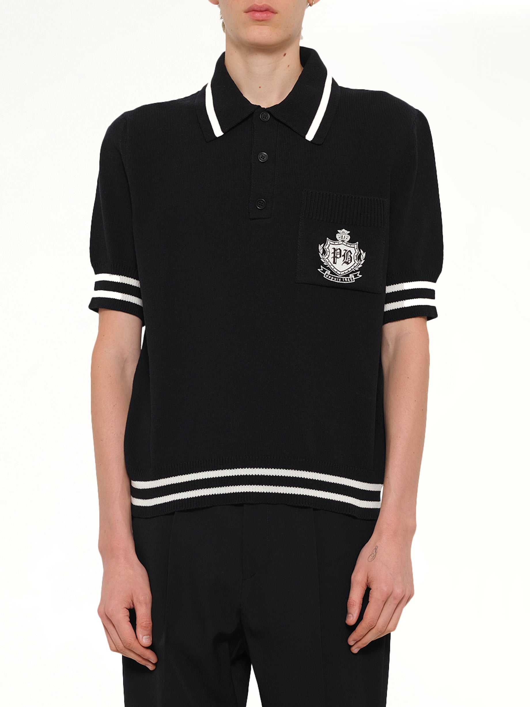 Image of a model wearing Tops. Product name - College Emblem Knit Polo in Black colour by brand - BALMAIN