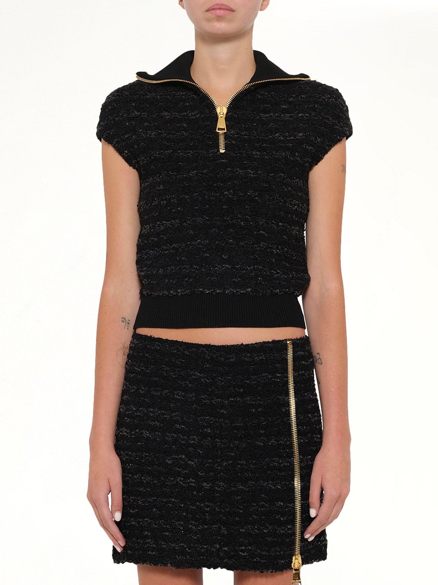 Image of a model wearing Tops. Product name - Zipped Short Sleeve Knit Tweed Top in Black colour by brand - BALMAIN