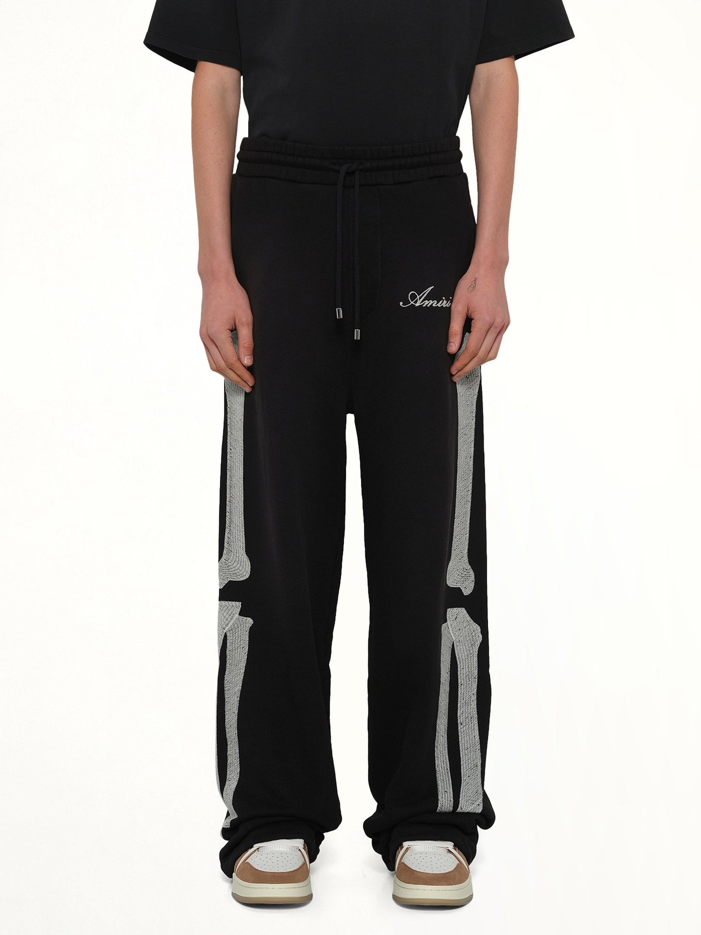 Image of a model wearing Pants. Product name - Bones Oversized Sweatpant in Black colour by brand - AMIRI