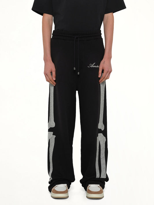Image of a model wearing Pants. Product name - Bones Oversized Sweatpant in Black colour by brand - AMIRI