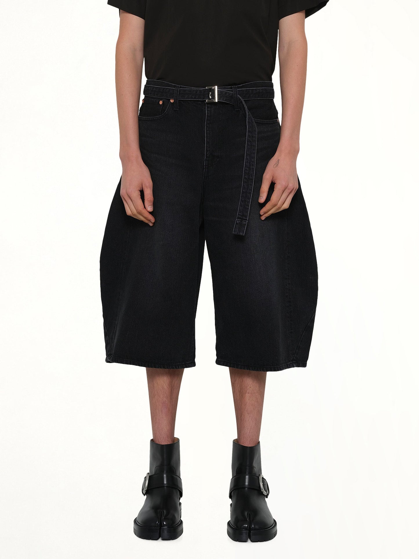 Image of a model wearing Shorts. Product name - Denim Bermuda in Black colour by brand - SACAI