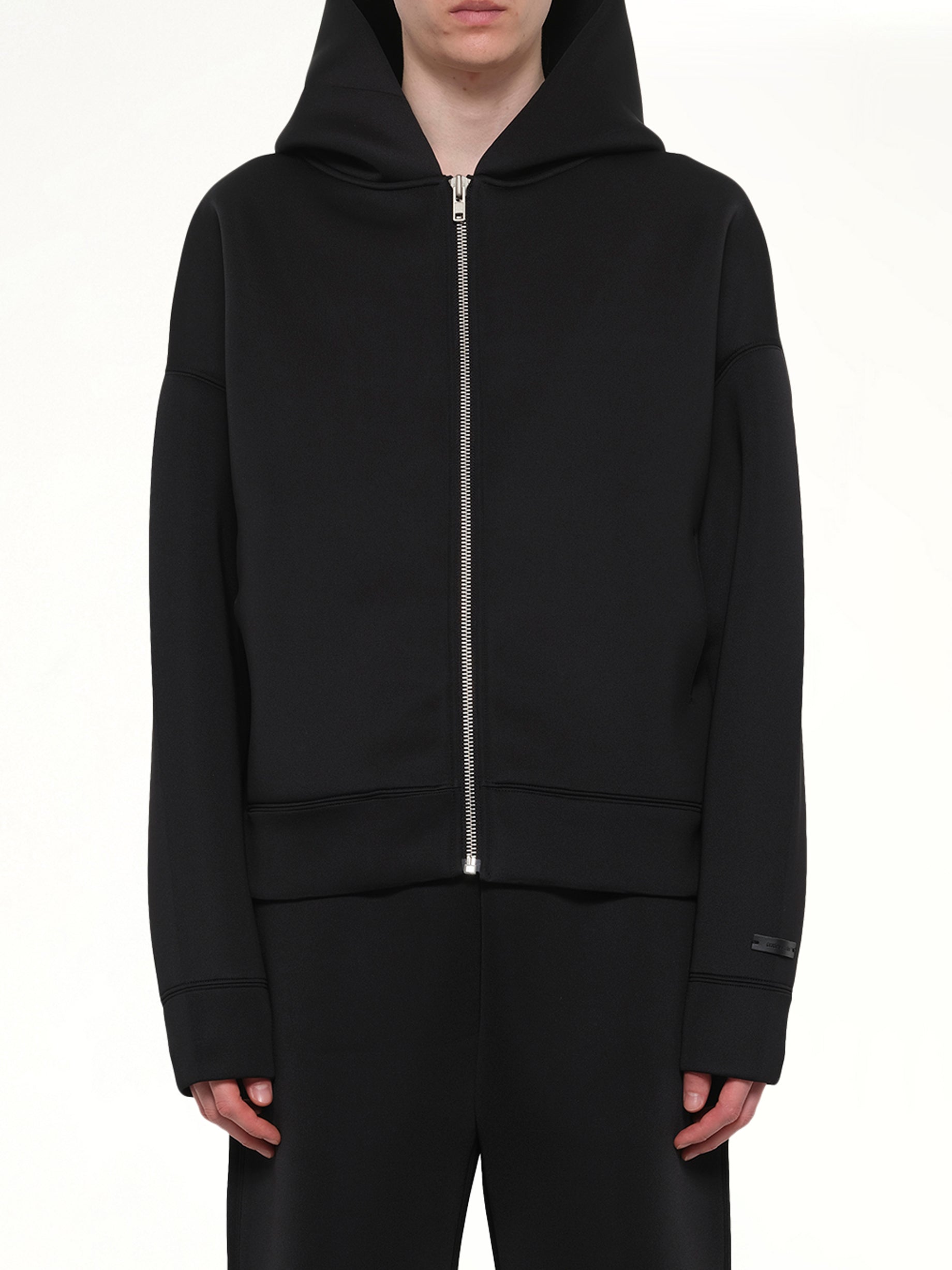 Image of a model wearing Outerwear. Product name - Scuba Zip Hood in Black colour by brand - ENTIRE STUDIOS